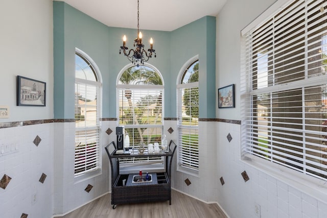 interior space with an inviting chandelier, hardwood / wood-style flooring, and tile walls