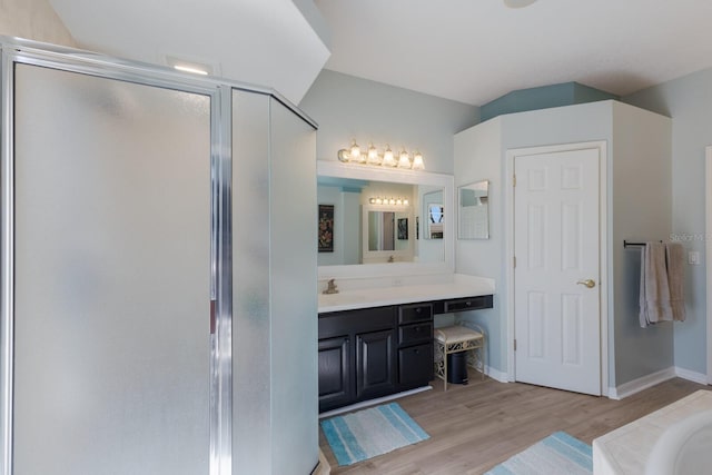 bathroom with hardwood / wood-style flooring, vanity, and plus walk in shower