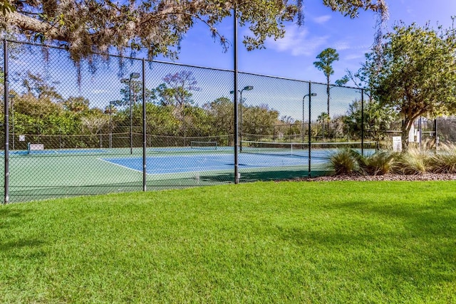 view of tennis court featuring a yard