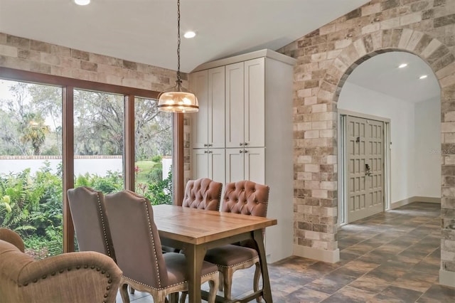 dining area featuring recessed lighting, stone finish floor, vaulted ceiling, baseboards, and arched walkways
