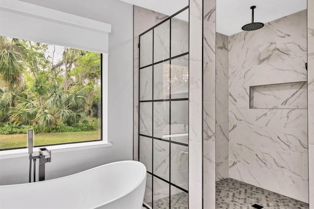 full bathroom featuring a freestanding tub and a marble finish shower