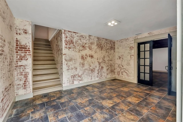 spare room with stairway, french doors, brick wall, and baseboards