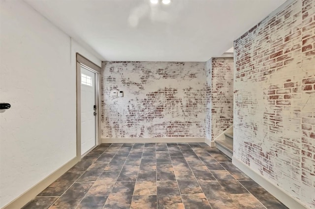 spare room with brick wall and baseboards