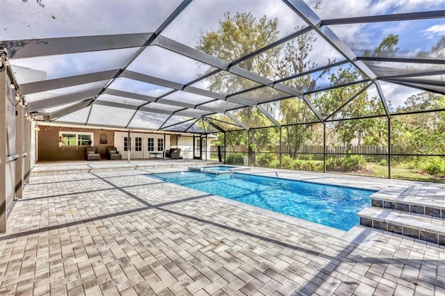 view of swimming pool featuring a lanai, a patio area, french doors, and a pool with connected hot tub