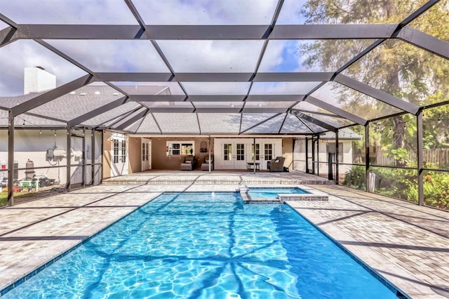 view of pool with a lanai, french doors, a pool with connected hot tub, and a patio area