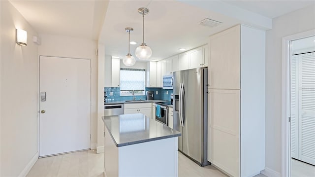 kitchen featuring a kitchen island, decorative light fixtures, sink, white cabinets, and stainless steel appliances