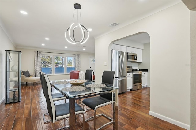 dining area featuring dark wood-type flooring and crown molding