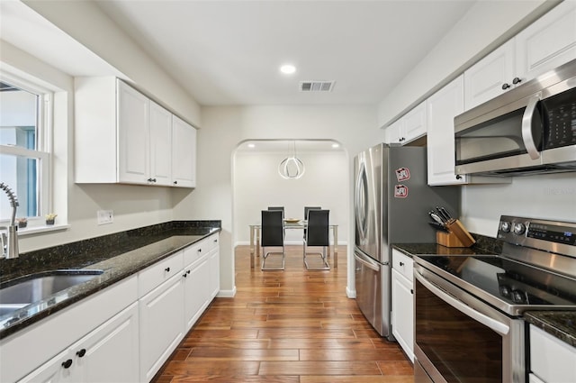 kitchen featuring dark stone countertops, stainless steel appliances, and white cabinets