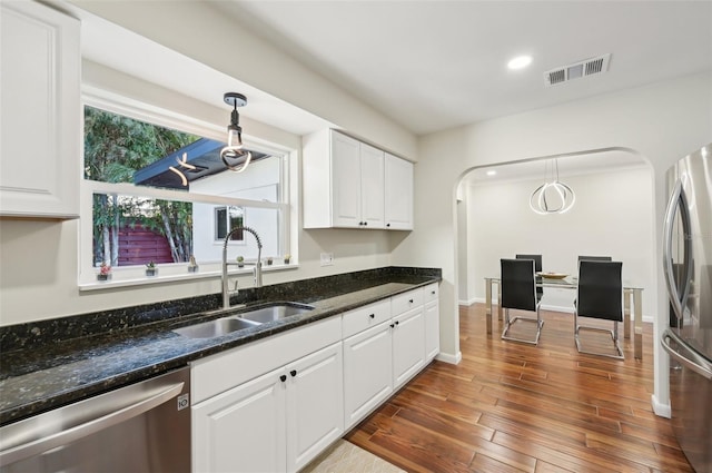 kitchen with sink, dark stone counters, pendant lighting, stainless steel appliances, and white cabinets