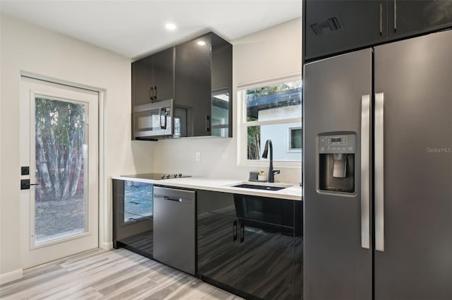 kitchen with stainless steel appliances, sink, and light hardwood / wood-style floors