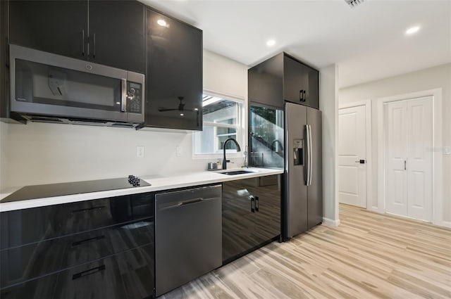 kitchen featuring sink, light hardwood / wood-style floors, and black appliances