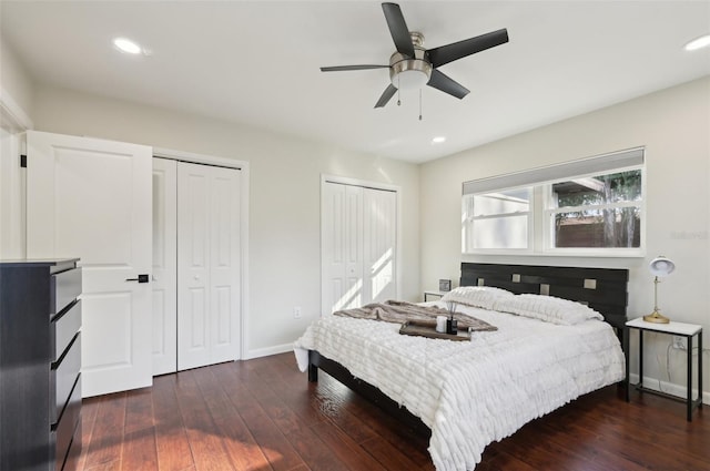 bedroom with ceiling fan, dark hardwood / wood-style flooring, and two closets