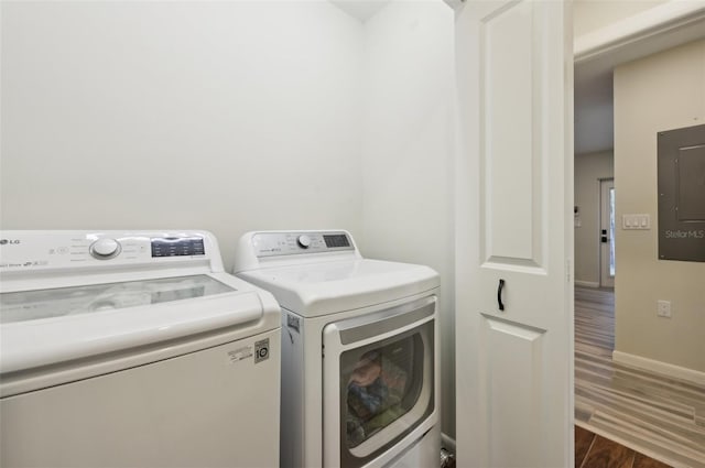 clothes washing area featuring dark hardwood / wood-style flooring, electric panel, and washing machine and clothes dryer