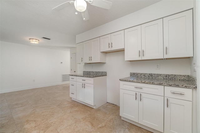 kitchen featuring ceiling fan, white cabinetry, and stone counters