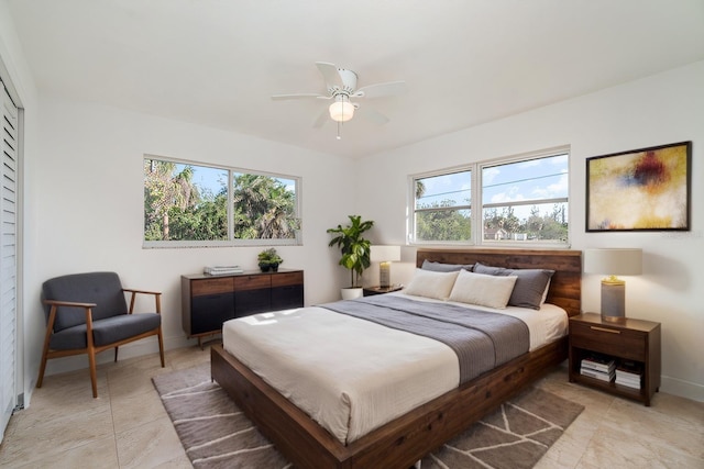 bedroom with ceiling fan, light tile patterned floors, and multiple windows