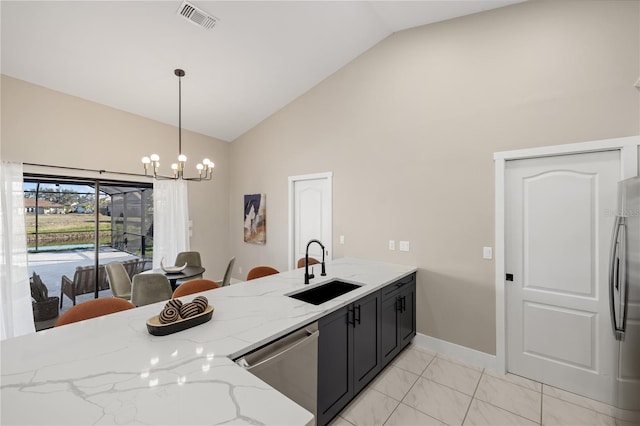 kitchen featuring appliances with stainless steel finishes, sink, hanging light fixtures, light stone counters, and an inviting chandelier