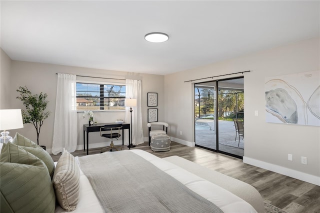 bedroom featuring multiple windows, hardwood / wood-style flooring, and access to outside