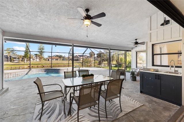 view of patio with ceiling fan, sink, and glass enclosure