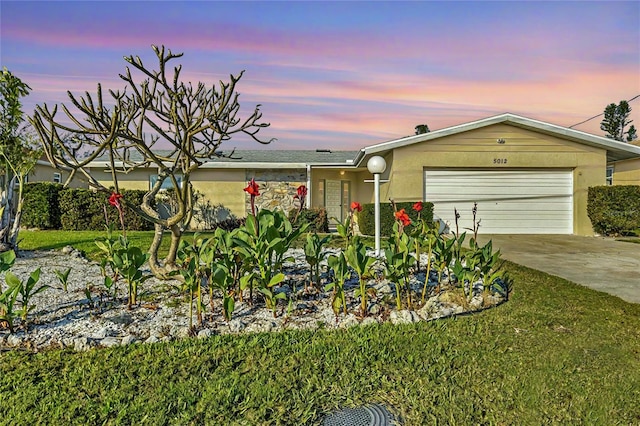 single story home featuring a garage and a lawn