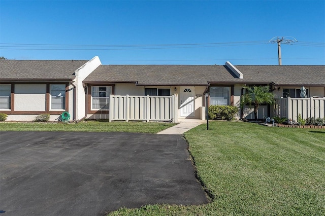 view of front of property featuring fence, a front lawn, and stucco siding