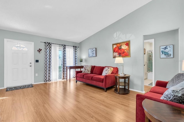 living area featuring light wood-style floors, lofted ceiling, and baseboards