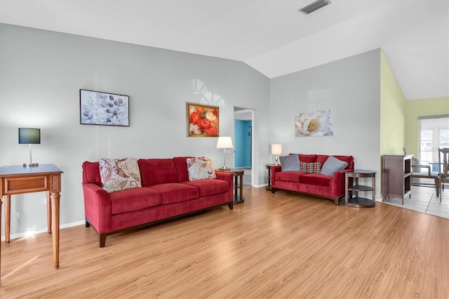 living area featuring lofted ceiling, wood finished floors, visible vents, and baseboards