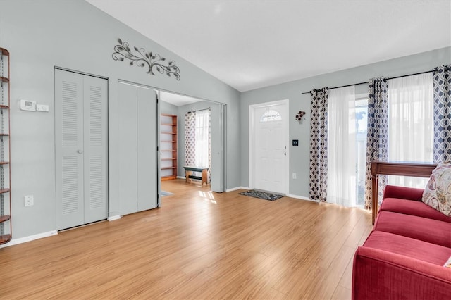 living room featuring lofted ceiling, plenty of natural light, baseboards, and light wood-style floors