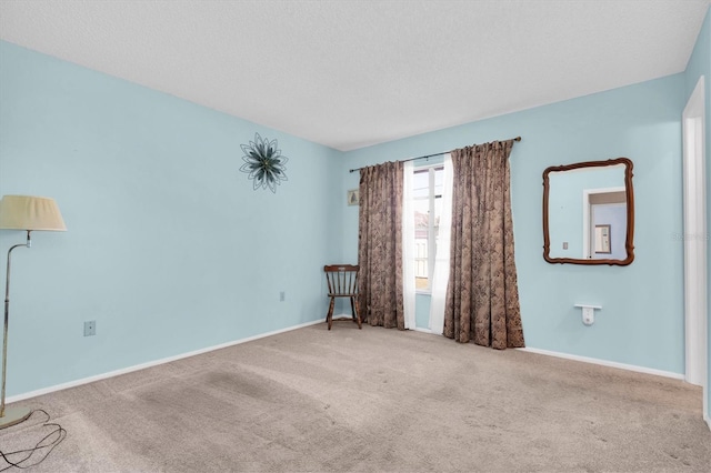 empty room featuring a textured ceiling, carpet, and baseboards