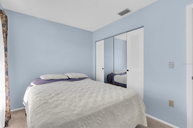 bedroom featuring baseboards, a closet, visible vents, and carpet flooring