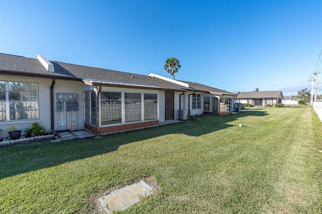 back of property with cooling unit, a lawn, and stucco siding