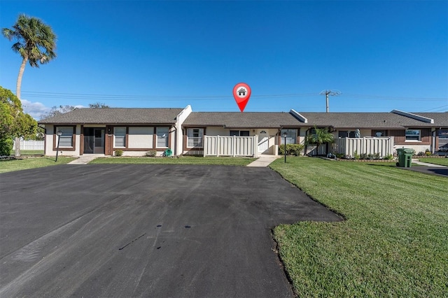 ranch-style home featuring a fenced front yard, a front lawn, and stucco siding