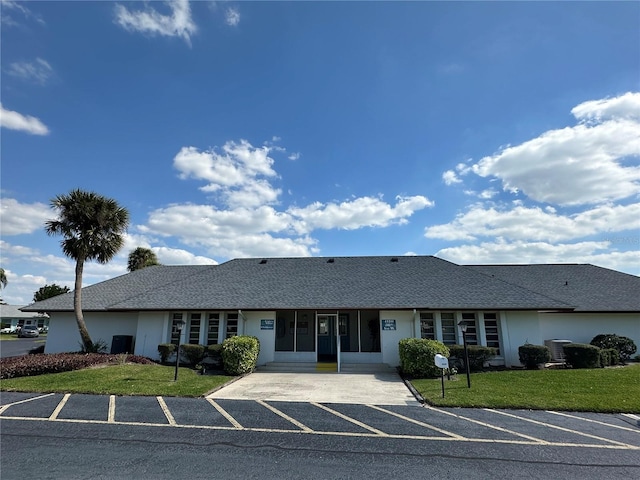 ranch-style home featuring central air condition unit, a sunroom, stucco siding, and a front yard