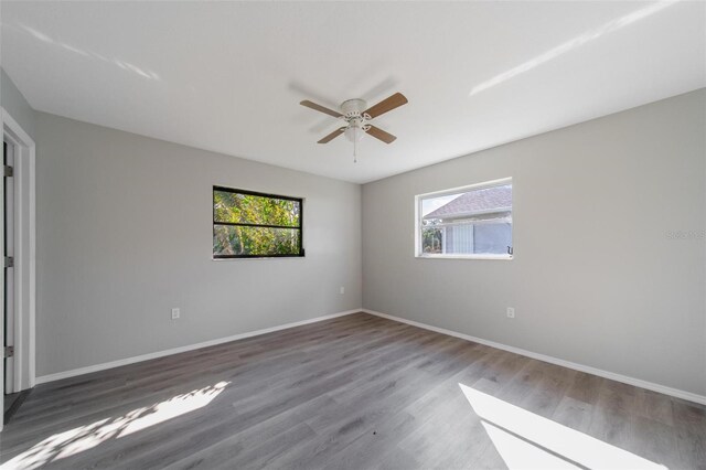 spare room with ceiling fan, dark wood-type flooring, and a healthy amount of sunlight