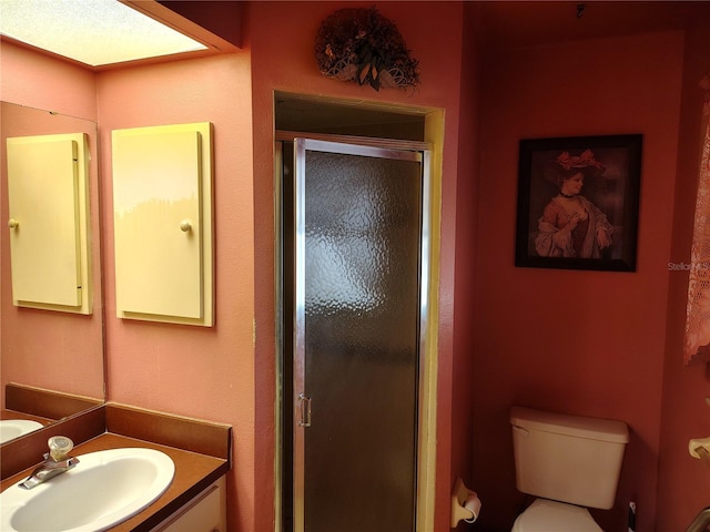 bathroom featuring vanity, a shower with shower door, and toilet