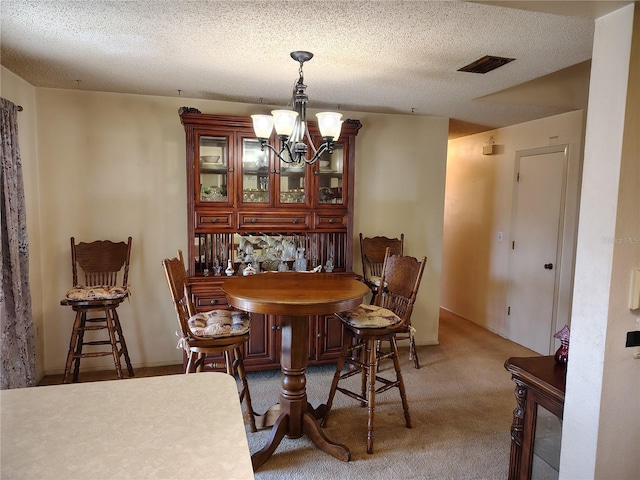 carpeted dining space featuring a textured ceiling and a chandelier