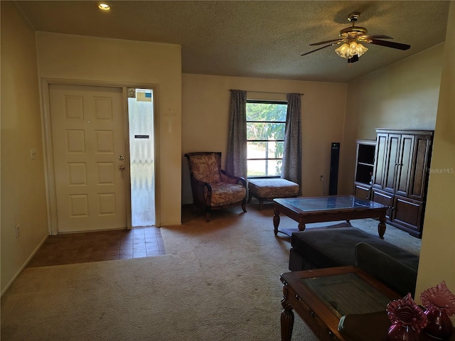 living room with ceiling fan, carpet flooring, and a textured ceiling