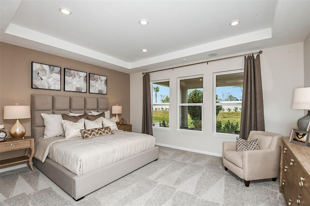 bedroom featuring light colored carpet and a tray ceiling