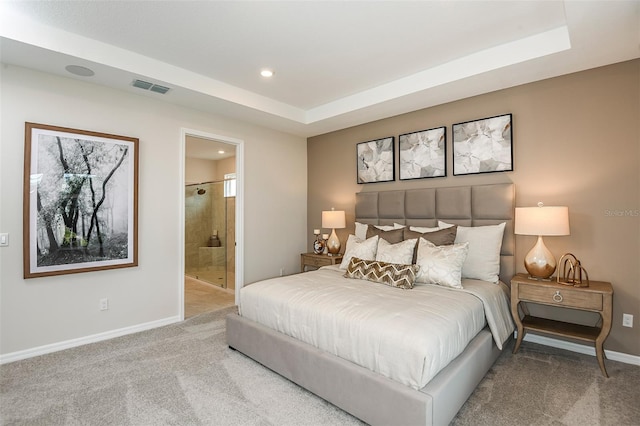 bedroom featuring a raised ceiling, ensuite bathroom, and carpet