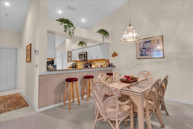 carpeted dining space with high vaulted ceiling