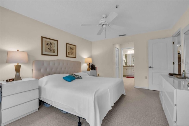 bedroom with light carpet, connected bathroom, and ceiling fan