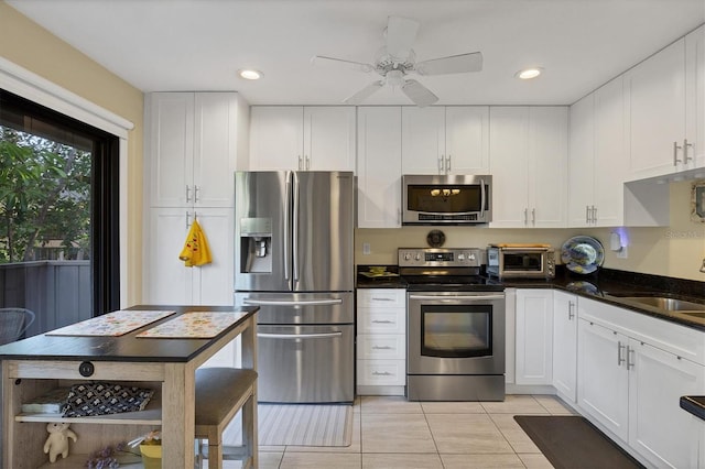 kitchen with light tile patterned flooring, sink, white cabinetry, ceiling fan, and stainless steel appliances