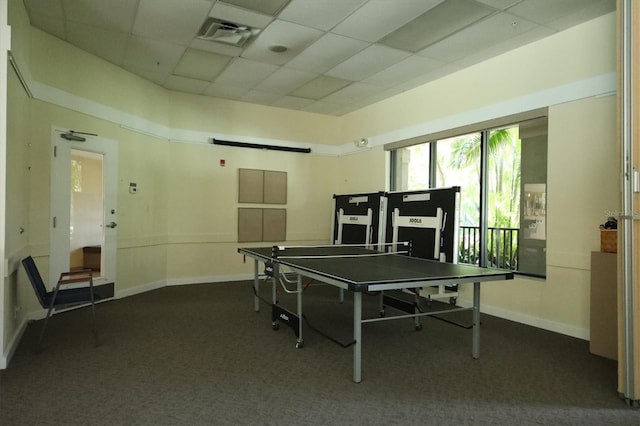 playroom featuring a barn door, a drop ceiling, and dark colored carpet