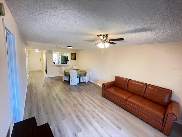 living room with a textured ceiling, light hardwood / wood-style flooring, and ceiling fan