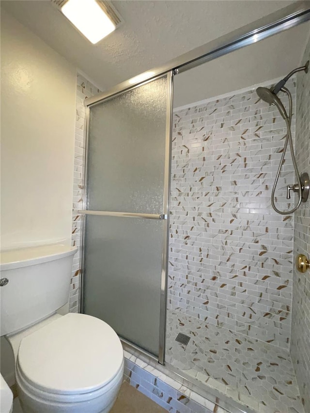 bathroom featuring toilet and a shower with shower door