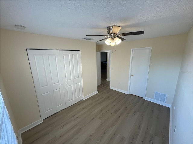 unfurnished bedroom featuring ceiling fan, hardwood / wood-style flooring, a closet, and a textured ceiling