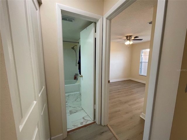 bathroom with shower / bath combination, ceiling fan, hardwood / wood-style flooring, and a textured ceiling