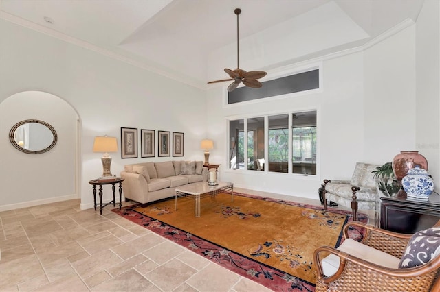 living room featuring baseboards, arched walkways, ceiling fan, stone finish floor, and a high ceiling