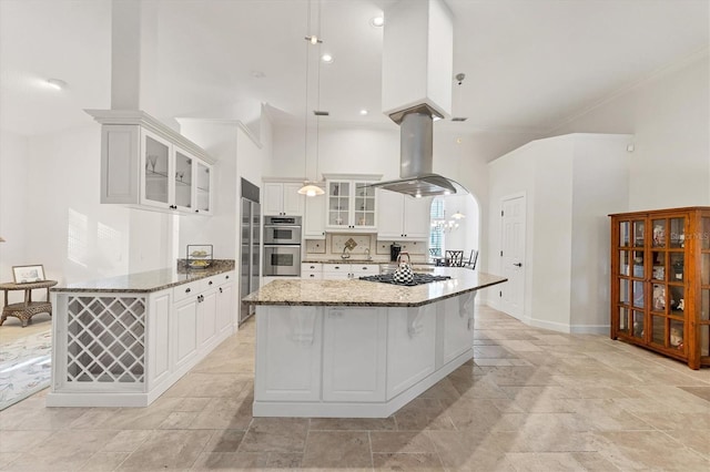 kitchen with stone counters, a high ceiling, white cabinetry, appliances with stainless steel finishes, and island exhaust hood