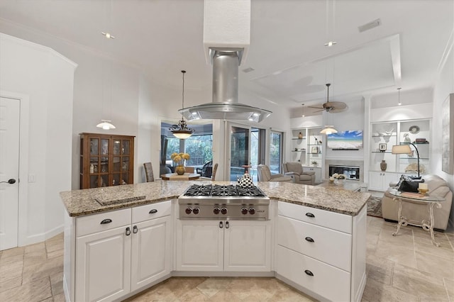 kitchen featuring light stone countertops, stainless steel gas cooktop, open floor plan, and a glass covered fireplace