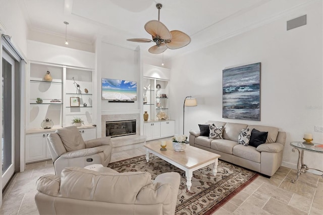 living room featuring visible vents, a glass covered fireplace, ceiling fan, stone finish floor, and ornamental molding